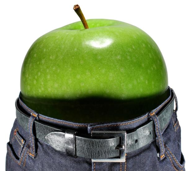 Ein grüner Apfel steckt in einer Jeanshose mit Gürtel.