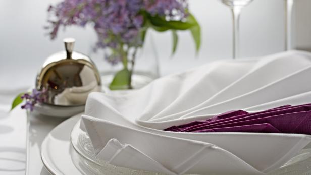 Ein elegant gedeckter Tisch mit weißen Servietten und einem Blumenarrangement.