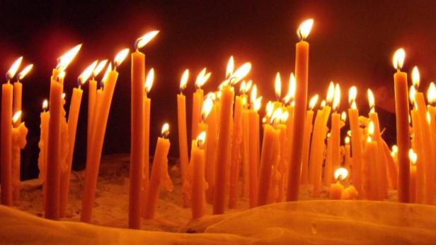 Viele brennende Kerzen stehen nebeneinander.