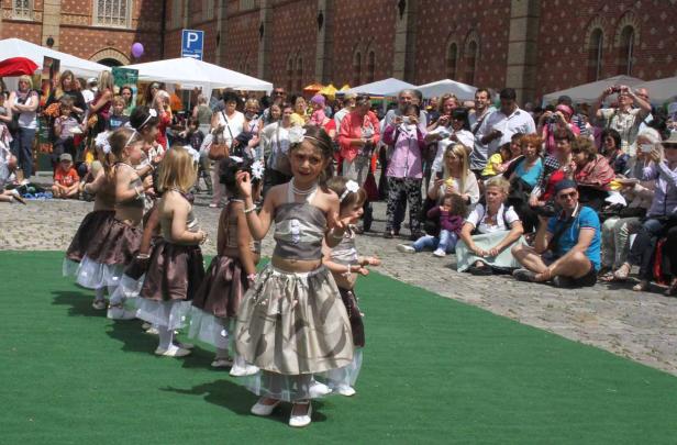 Eine Gruppe junger Mädchen führt eine Tanzdarbietung vor Publikum auf einer grünen Bühne auf.