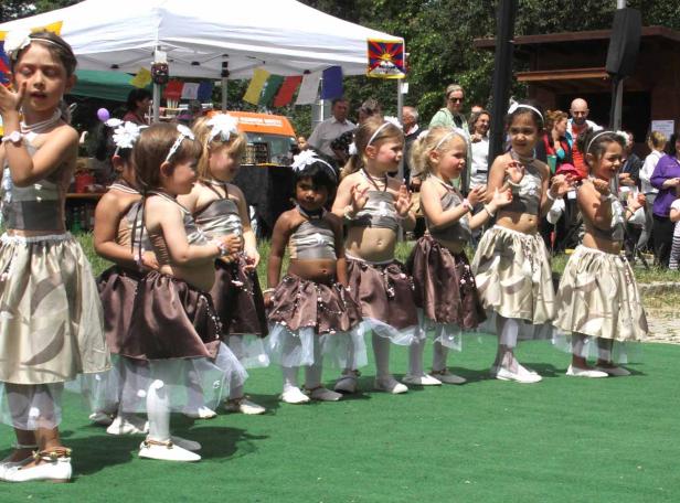 Eine Gruppe junger Mädchen in Kostümen führt einen Tanz im Freien auf.