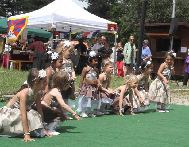 Eine Gruppe junger Mädchen in Kostümen tritt auf einer grünen Bühne auf.