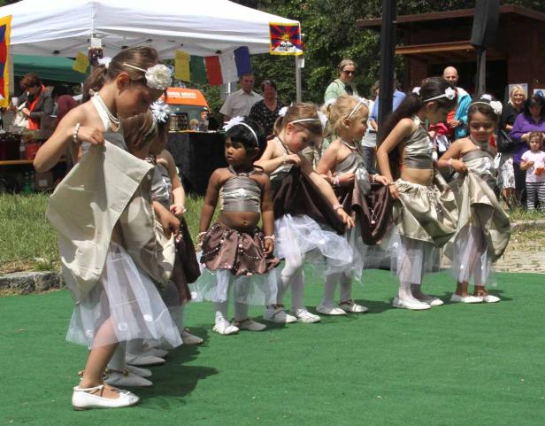 Eine Gruppe junger Mädchen in Kostümen führt einen Tanz im Freien auf.