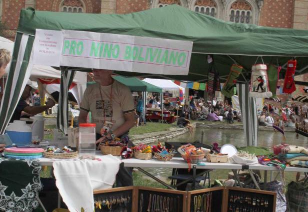Ein Marktstand von „Pro Nino Boliviano“ mit Kunsthandwerk und einem Teich im Hintergrund.
