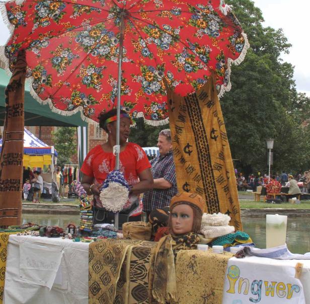 Eine Frau verkauft unter einem blumengemusterten Sonnenschirm Waren auf einem Markt.