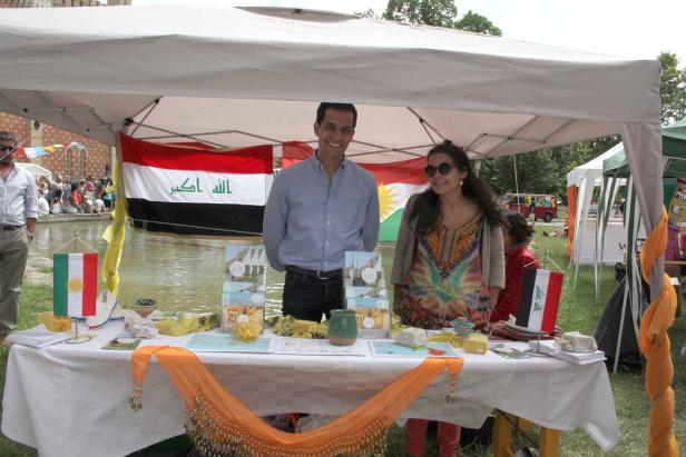 Ein Mann und eine Frau stehen an einem Stand mit irakischen und kurdischen Flaggen.