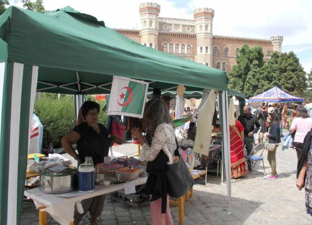 Ein Marktstand mit algerischer Flagge vor einem historischen Gebäude.