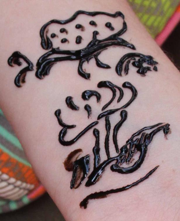 Auf einem Arm befindet sich eine temporäre Tätowierung mit floralen Motiven.