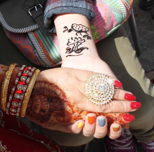 Zwei Frauenhände mit Henna-Tattoos, Schmuck und Nagellack in verschiedenen Farben.