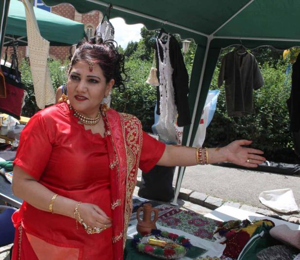 Eine Frau in traditioneller roter Kleidung steht an einem Verkaufsstand.