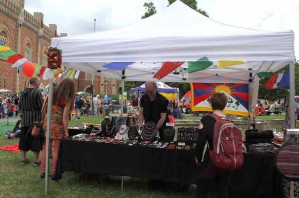 Ein Marktstand mit Schmuck und Textilien unter einem weißen Zelt mit tibetischen Gebetsfahnen.