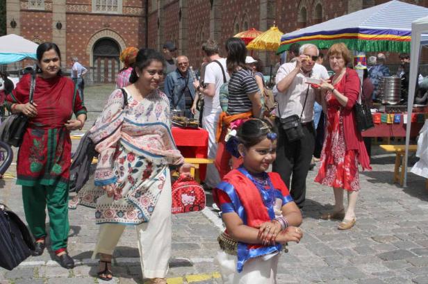 Eine junge Frau in traditioneller Kleidung steht auf einem belebten Platz.