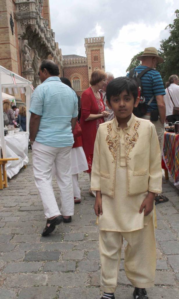 Ein Junge in traditioneller Kleidung steht vor einem Gebäude.