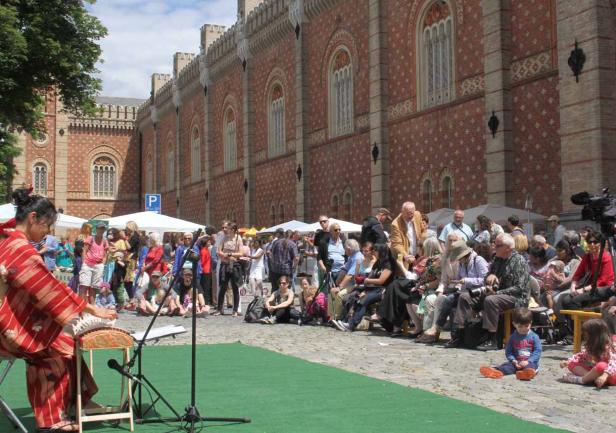 Eine Frau im Kimono spielt ein traditionelles japanisches Instrument vor Publikum.