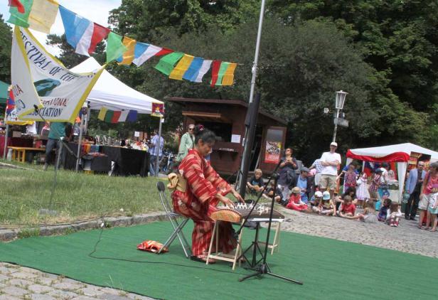Eine Frau im Kimono spielt ein traditionelles japanisches Instrument vor Publikum.