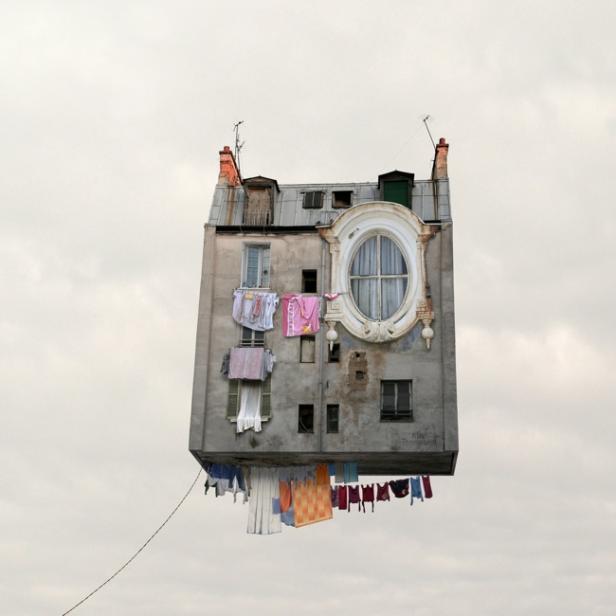 Ein surreales Gebäude schwebt mit Wäscheleinen unter dem Himmel.