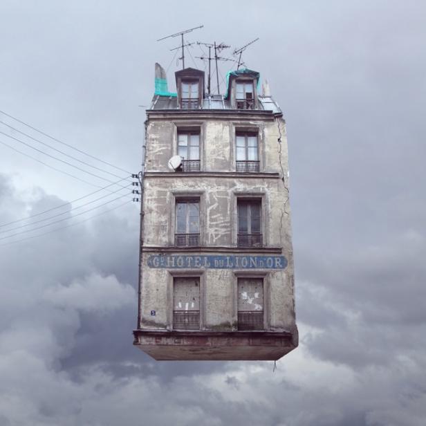 Ein Gebäude mit der Aufschrift „Hotel du Lion d'Or“ schwebt vor einem bewölkten Himmel.