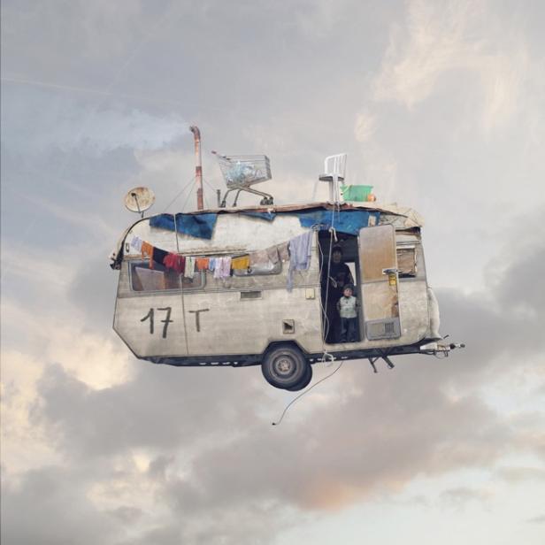 Ein heruntergekommener Wohnwagen schwebt mit einer Familie darin durch den Himmel.