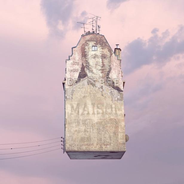 Ein Gebäude mit einem verblichenen Werbeporträt vor einem rosafarbenen Himmel.