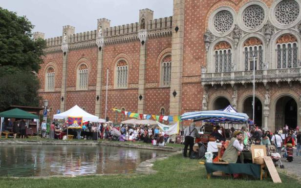 Ein Markt findet vor einem historischen Gebäude mit einem kleinen Teich statt.