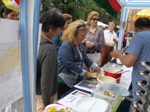 An einem Stand probieren mehrere Personen Speisen und Getränke.