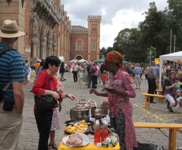 Eine Frau verkauft Essen an einem Stand auf einem belebten Platz vor einem Gebäude.