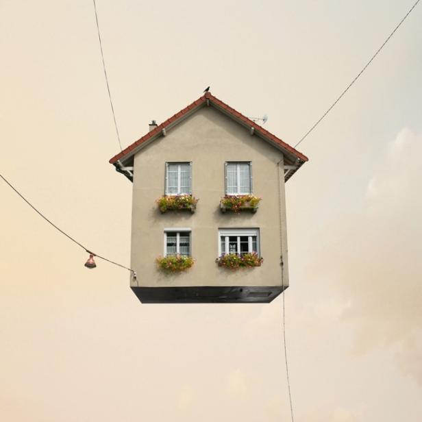 Ein Haus mit Blumenkästen an den Fenstern schwebt in der Luft.
