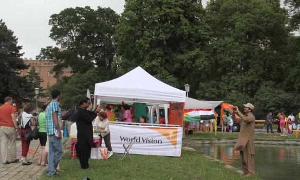 Menschen besuchen einen Stand von World Vision an einem See.