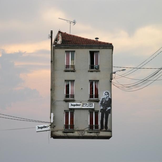 Ein surreal wirkendes Gebäude mit der Aufschrift „Jupiler Hotel Cafe Restaurant“ schwebt in der Luft.