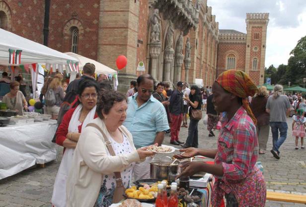 Eine Frau verkauft Essen auf einem Markt vor einem Backsteingebäude.