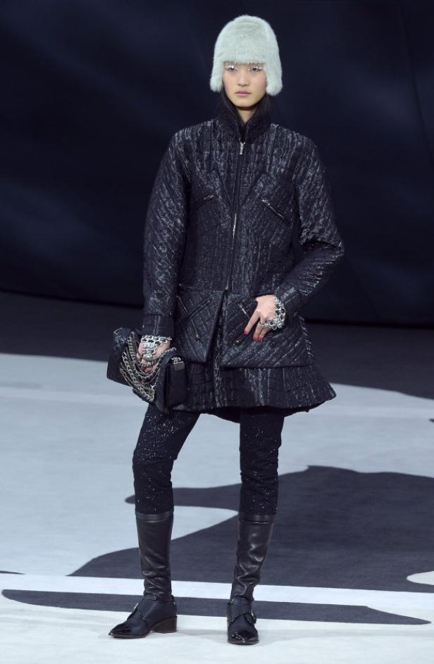 Eine Frau mit Pelzmütze präsentiert ein Outfit mit gesteppter Jacke und Stiefeln.