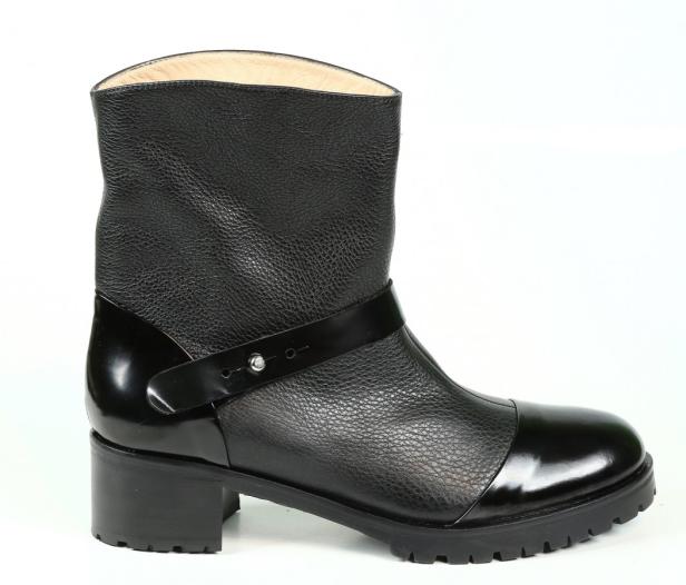 Ein schwarzer Lederstiefel mit Absatz und einem Riemen liegt auf einem weißen Hintergrund.