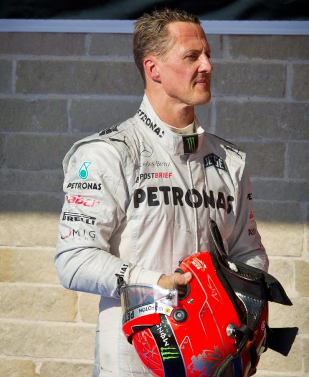 Michael Schumacher im Rennanzug mit seinem Helm in der Hand.