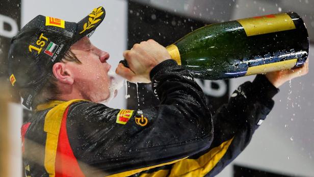 Ein Rennfahrer trinkt Champagner aus einer großen Flasche.