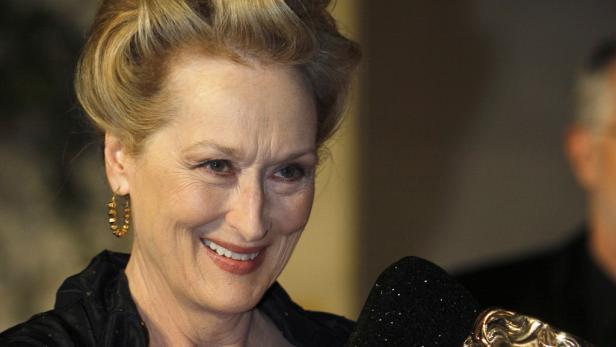 Ein Porträt von Meryl Streep, die lächelt und goldene Ohrringe trägt.