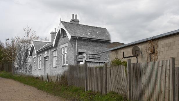 Ein Haus mit einem Anbau und einem Basketballkorb im Garten.