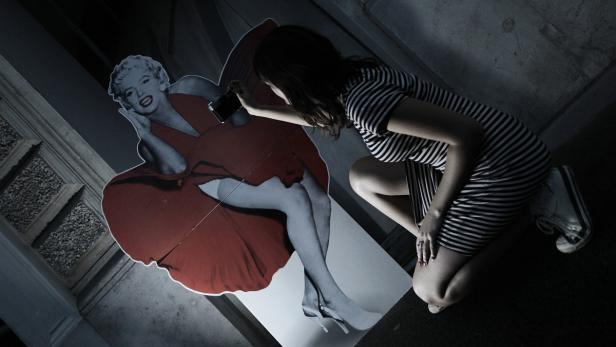 Eine Frau fotografiert eine Pappfigur von Marilyn Monroe.