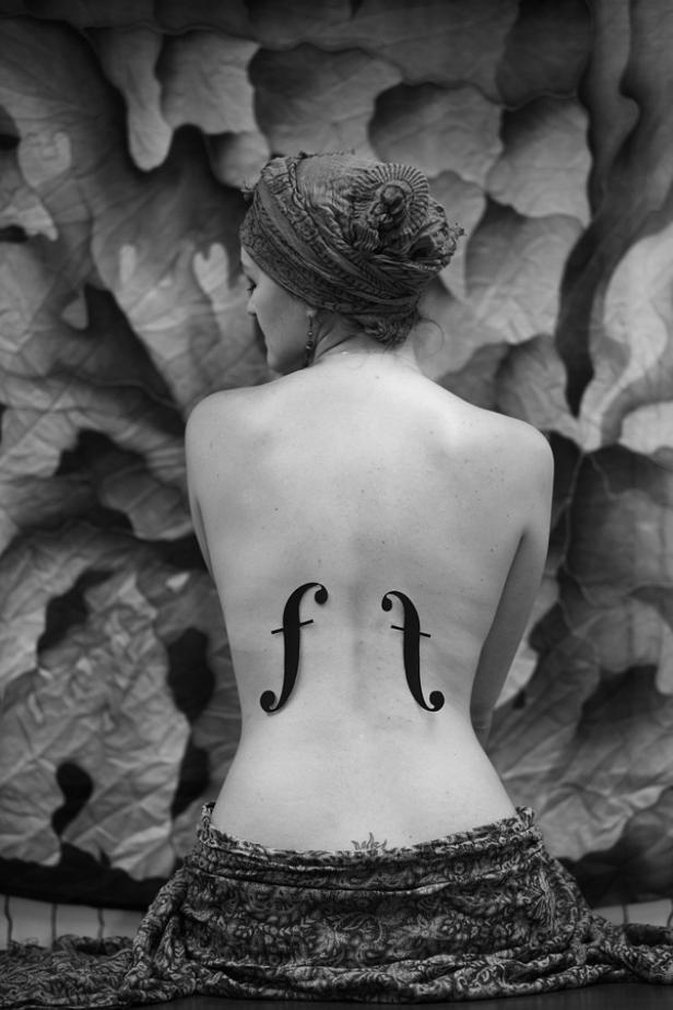 Rückenansicht einer Frau mit aufgemalten Violinschlüsseln und einem Turban.