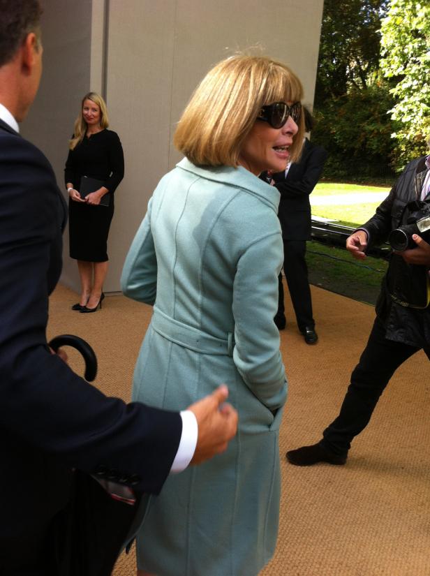 Anna Wintour trägt einen hellblauen Mantel und eine Sonnenbrille.