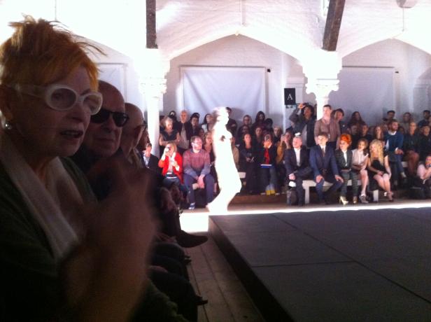 Eine Modenschau mit Zuschauern und einem Model im hellen Licht.