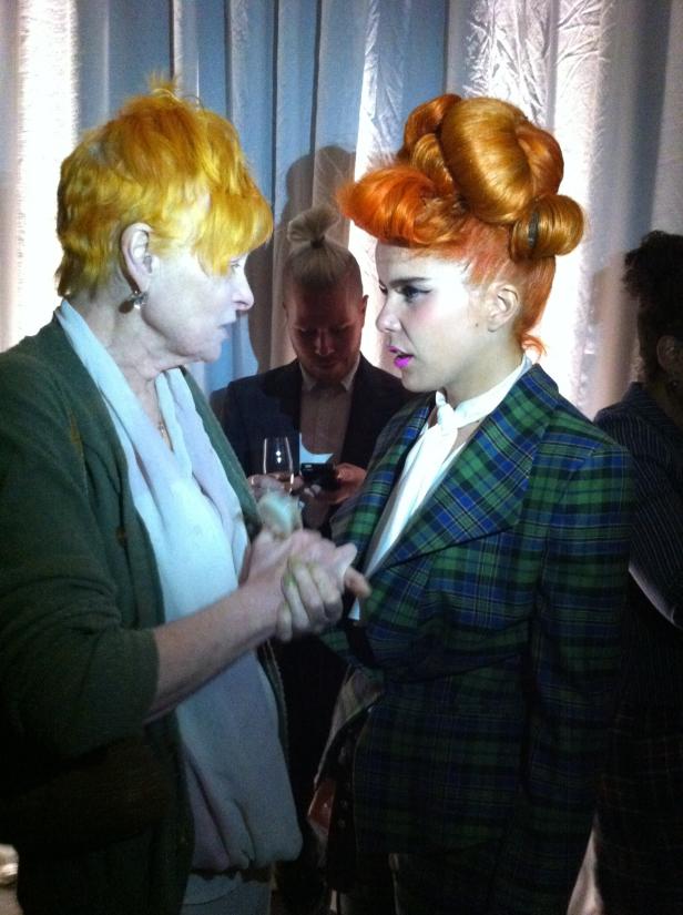 Zwei Frauen mit auffälligen Frisuren halten Hände.