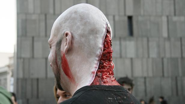 Ein Mann mit einem Make-up-Reißverschluss am Hinterkopf, der eine offene Wunde darstellt.