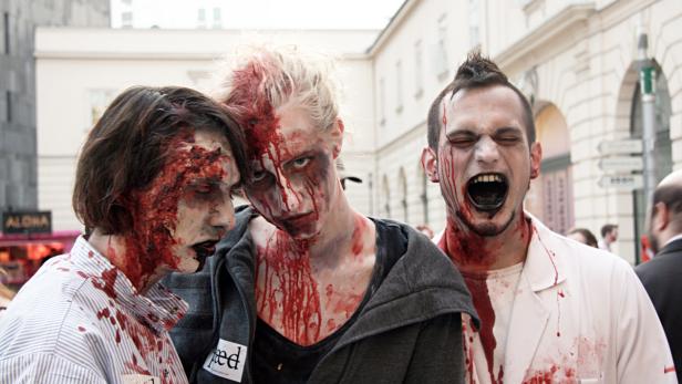 Drei als Zombies geschminkte Personen stehen auf der Straße.