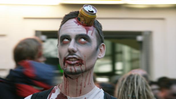 Ein Mann, als Zombie geschminkt, mit einer Getränkedose im Kopf.