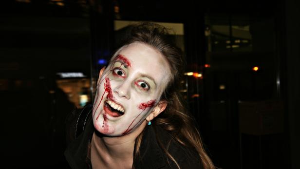 Eine Frau mit blutigem Zombie-Make-up blickt in die Kamera.