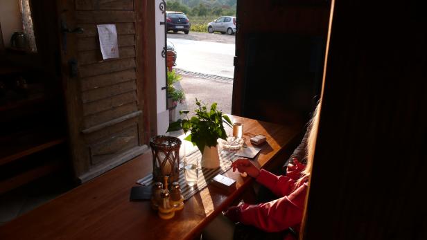 Eine Person sitzt an einem Tisch in einem Restaurant mit Blick auf die Straße.