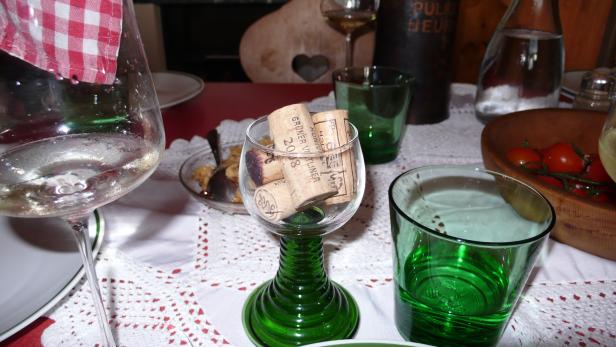 Ein gedeckter Tisch mit Weingläsern, grünen Gläsern und einer Schale mit Tomaten.