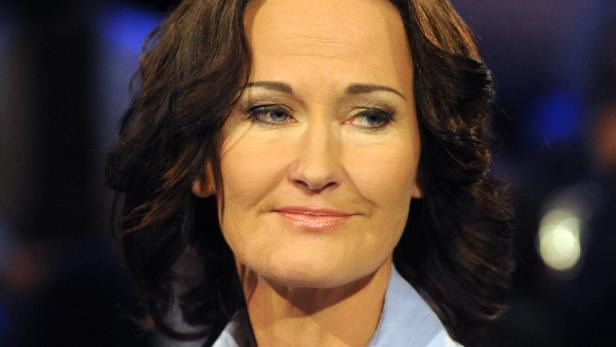 Nahaufnahme einer Frau mit braunen Haaren und blau-grauen Augen.