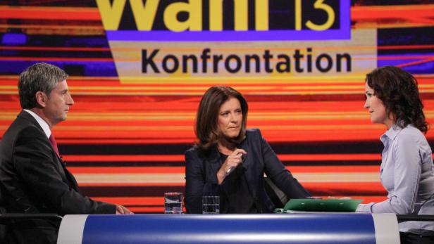 Drei Personen sitzen an einem Tisch vor dem Hintergrund einer Fernsehsendung zum Thema „Konfrontation“.