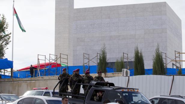 Militärpersonal steht auf einem Pickup-Truck vor einem Gebäude mit arabischer Schrift und einer palästinensischen Flagge.